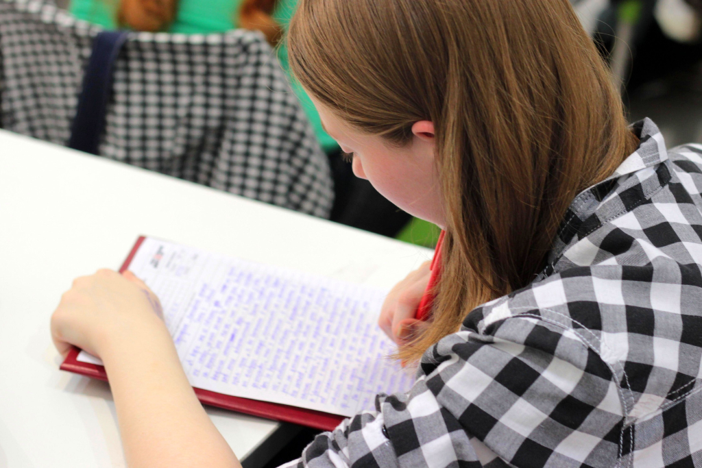 Estudante usando seus conhecimentos em redação para redigir um texto em sala de aula