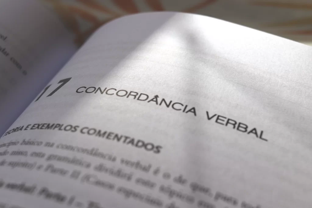 Livro de gramática para concursos públicos aberto na página onde se lê 'concordância verbal'