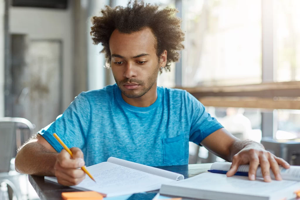 Candidato de concurso público faz anotações em caderno enquanto estuda com exercícios de concordância verbal com gabarito