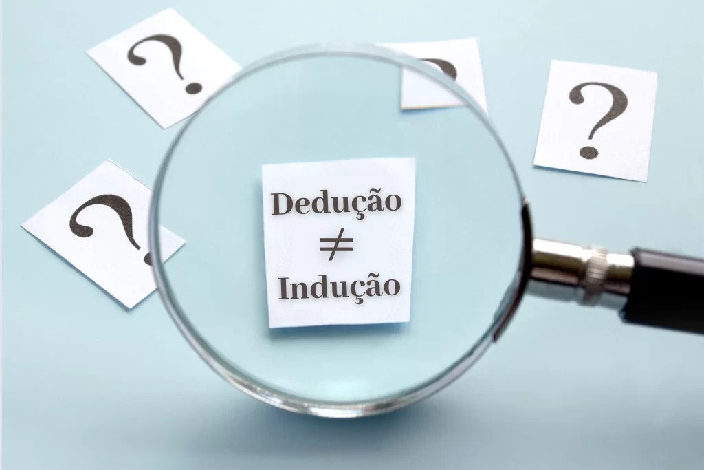Lupa ampliando papel branco onde está escrito 'dedução ≠ indução' sobre uma superfície azul-clara 