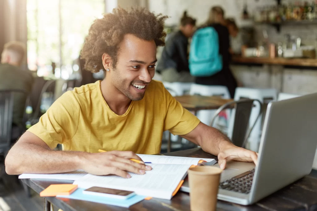 Homem olha sorridente para a tela do notebook enquanto estuda frases para usar na redação de concurso público
