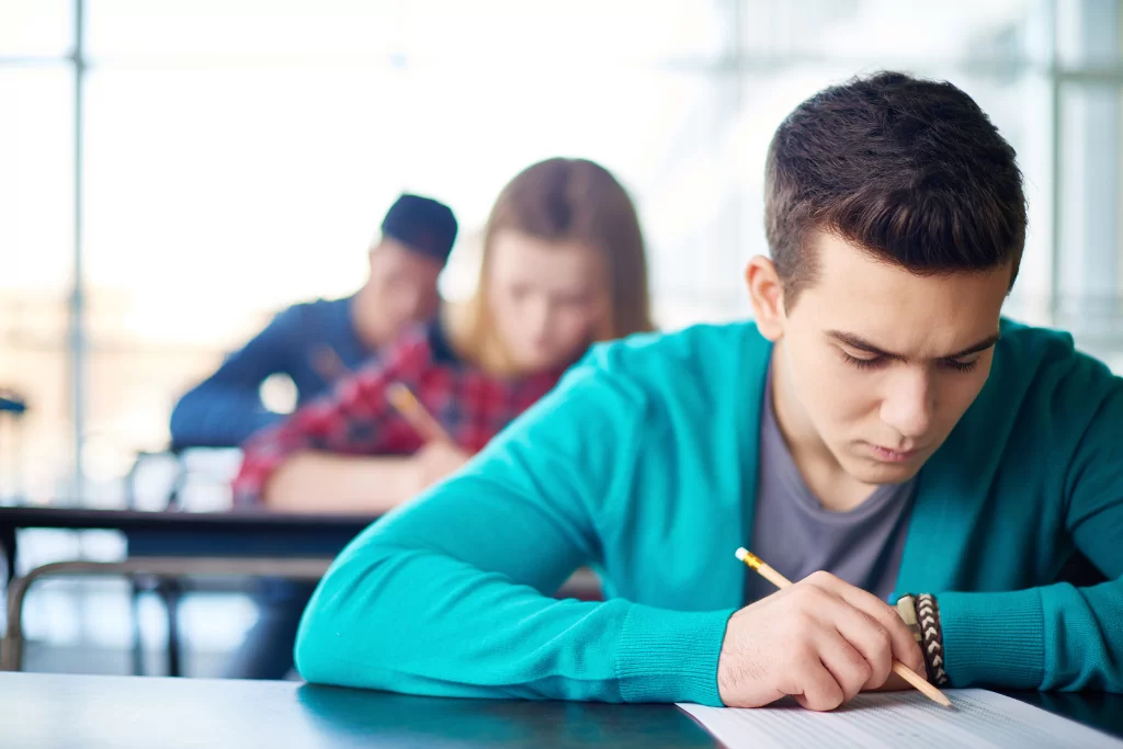 Alunos concentrados lendo a folha de respostas de concurso público da banca FCC