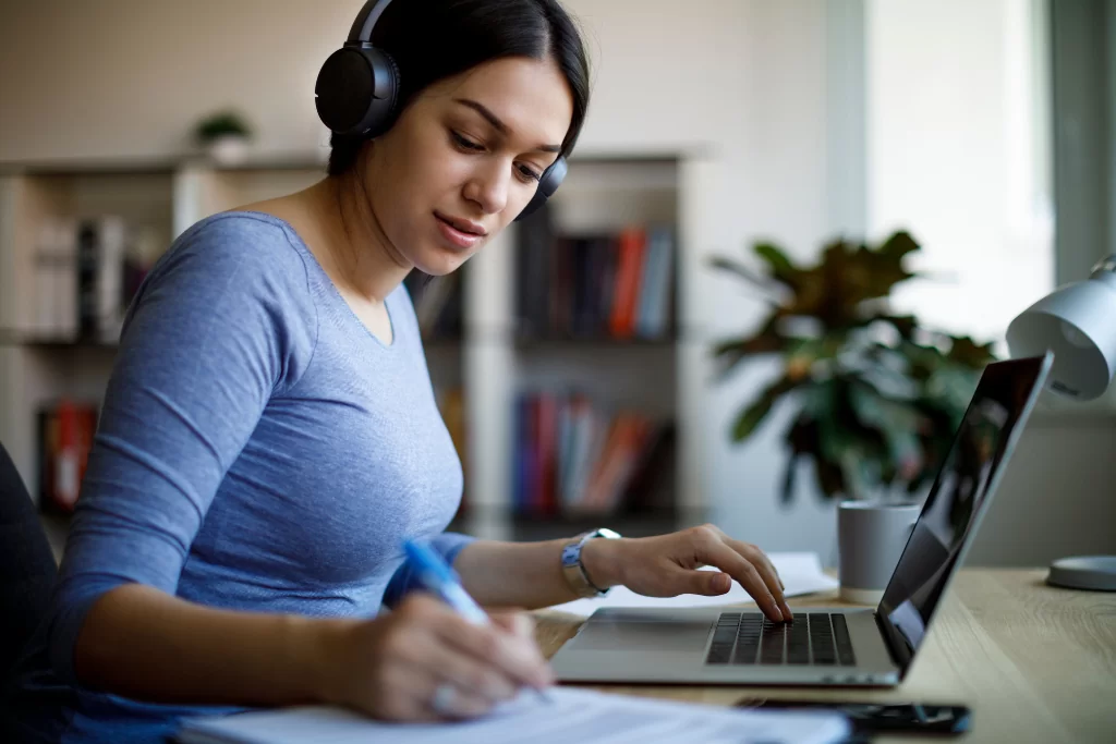 Mulher faz anotações em caderno enquanto estuda a diferença entre dedução e indução em curso online de português