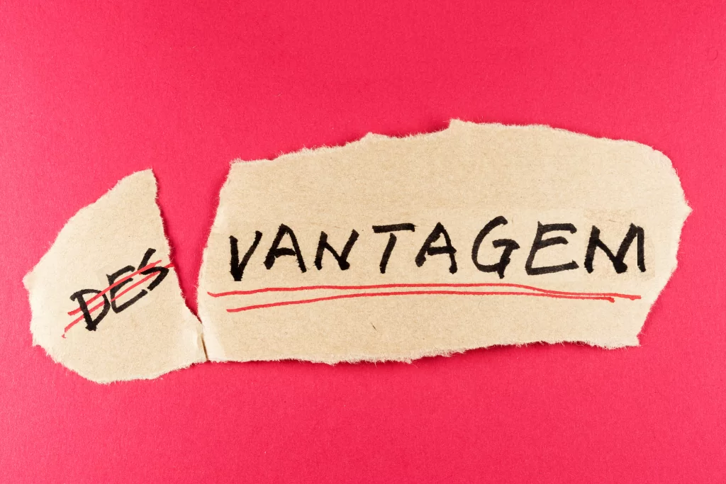 Papel rasgado com a inscrição 'desvantagem' sob uma superfície rosa.