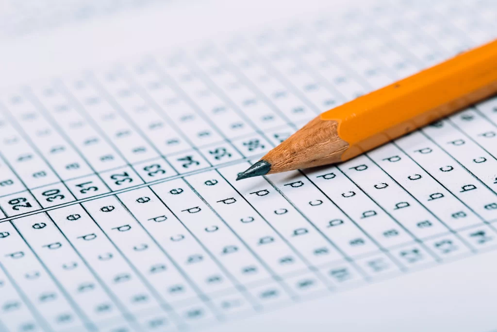 Lápis grafite amarelo em cima de gabarito de prova de concurso público com questões de crase