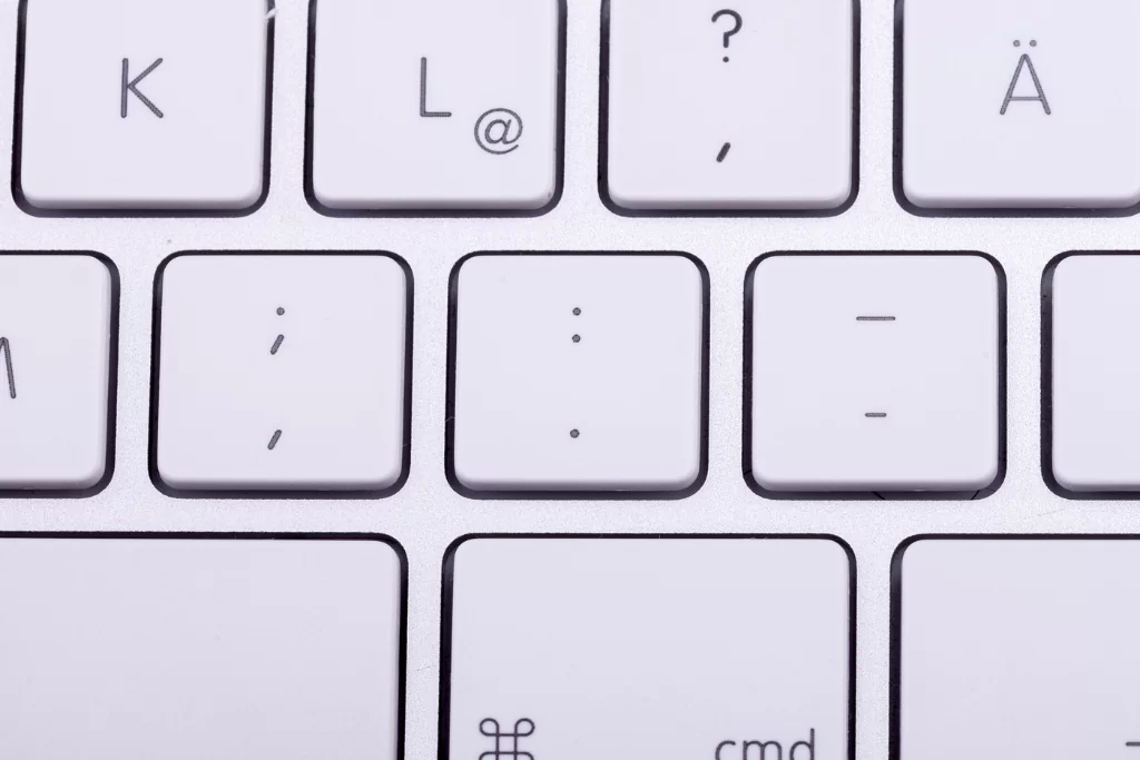 Teclas de um notebook branco com sinais de pontuação gramatical centralizados.