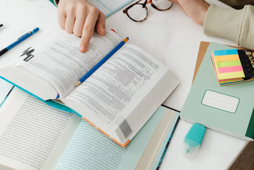 Concurseiro aponta para a página de um livro aberto enquanto estuda recorrência e inferência