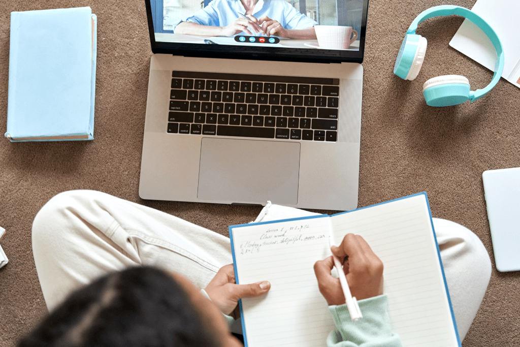 Estudante faz anotações em caderno enquanto estuda plural dos substantivos compostos exercícios no notebook