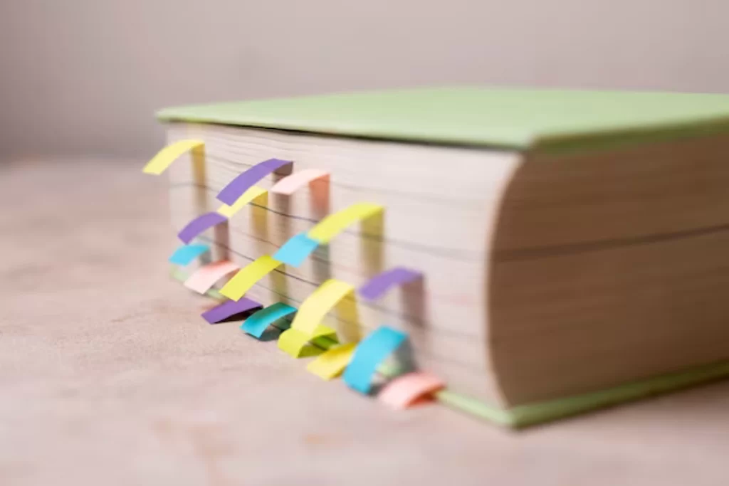 Livro fechado de capa verde com alguns papéis adesivos coloridos marcando o assunto de Português para concursos do zero 