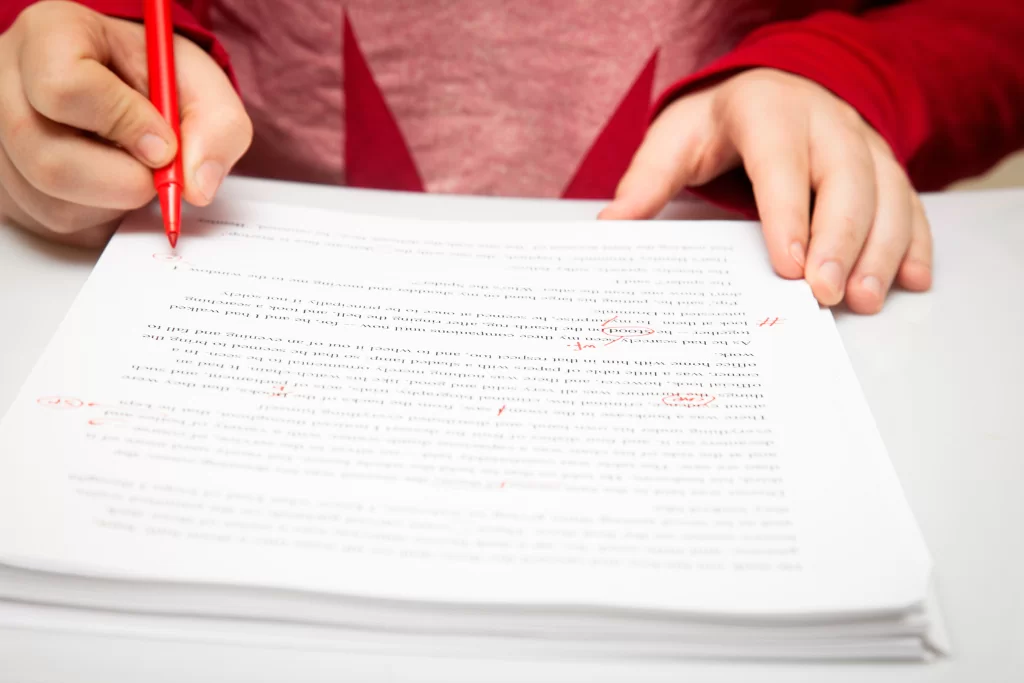 Concurseiro de blusa vermelha assinala prova com questões Cebraspe com lápis vermelho