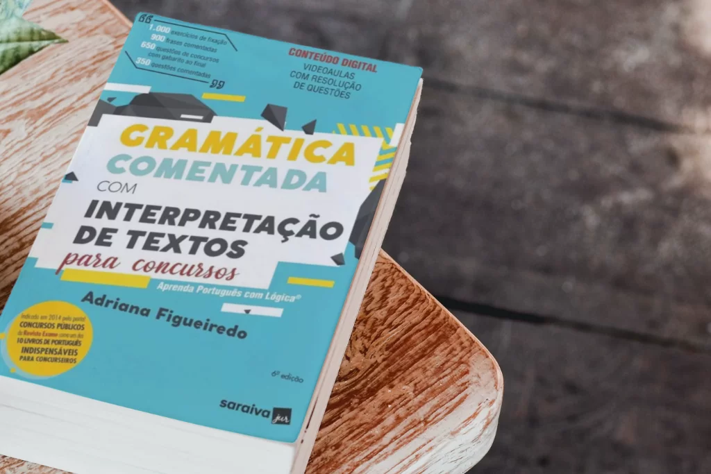 Gramática com questões Cebraspe de capa azul posicionado sobre uma mesa de madeira