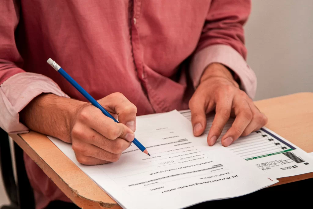 Concurseiro respondendo ao gabarito com um lápis azul em um papel com questões sobre tipos de discurso.